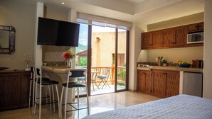 Habitación de hotel con balcón, cocina y televisión.