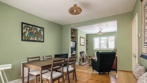 Un comedor con una mesa y sillas de madera, una pared verde y una lámpara de techo tejida.