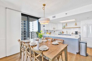 Een moderne keuken met witte kasten, een groot eiland en een eethoek met een houten tafel en stoelen.