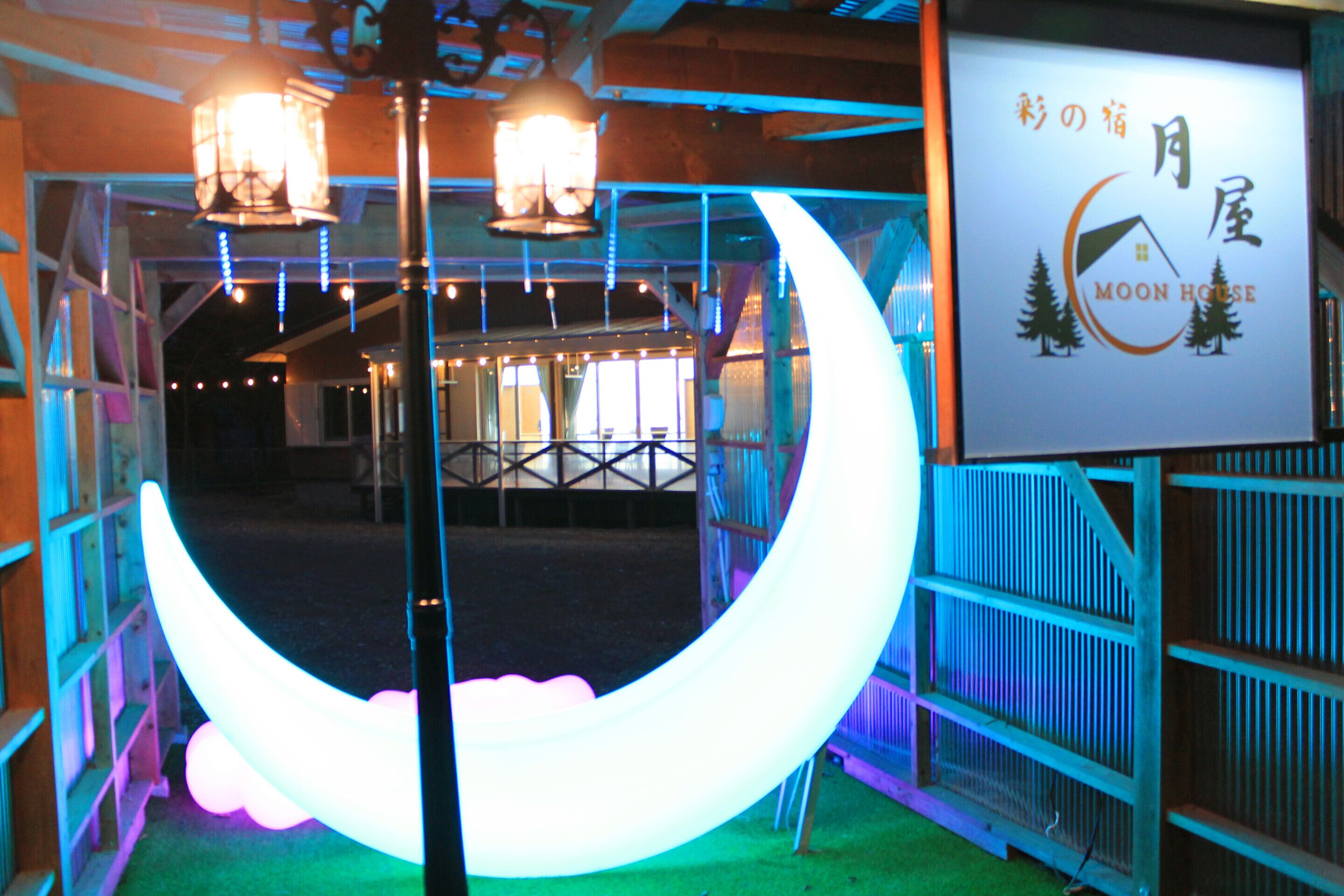 A hotel interior with a crescent moon decoration, a sign with 'MOON HOUSE' text, and a wooden structure.