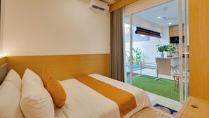 A hotel room with a bed, a ceiling fan, an air conditioning unit, and a view of a balcony with a plant and a TV. - Villa D'Bonzai - Nusa Dua (Nusa Dua)