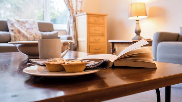 Ein gemütliches Wohnzimmer mit einem Holztisch, einem Buch und Muffins.