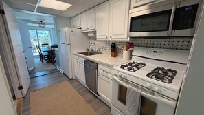 Una cocina moderna con alacenas blancas, electrodomésticos de acero inoxidable y vista al área de comedor.