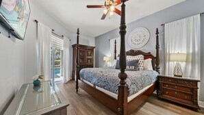 Ein Himmelbett mit Deckenventilator, einer Wanduhr und Blick ins Freie durch ein Fenster.