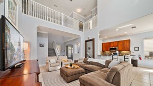 Ein geräumiges Wohnzimmer mit einem großen Ecksofa, einer Holz-Entertainmentanlage und einer Treppe, die zu einer oberen Ebene führt.