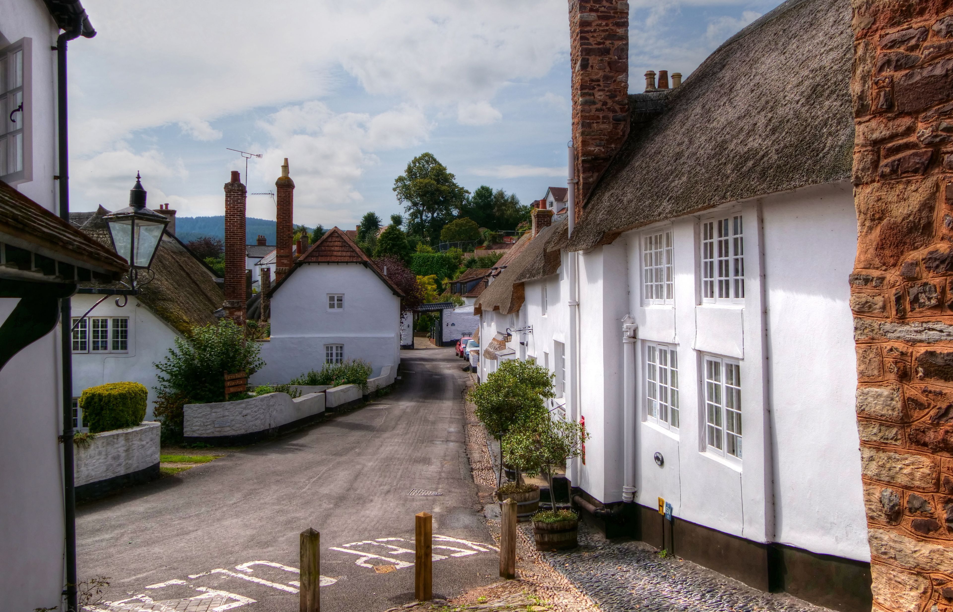 A narrow street lined with traditional white buildings with thatched roofs and stone walls.