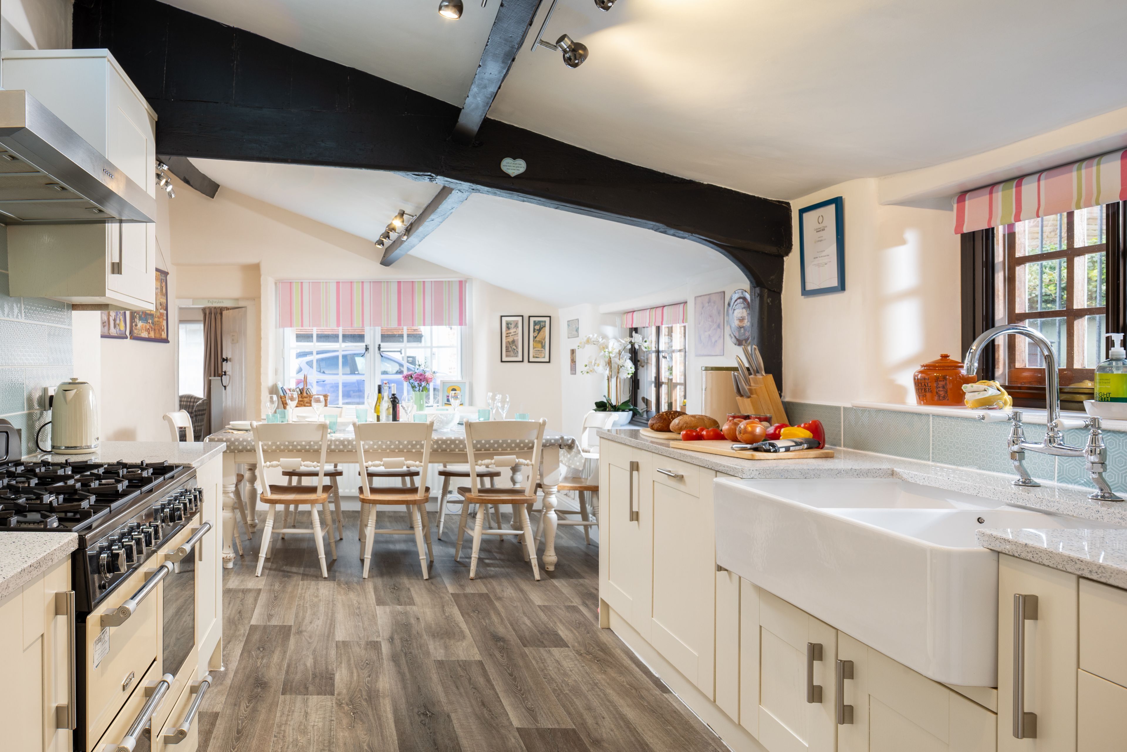 Een moderne keuken met houten vloeren, witte kastjes en een groot eiland met een spoelbak en aanrecht.