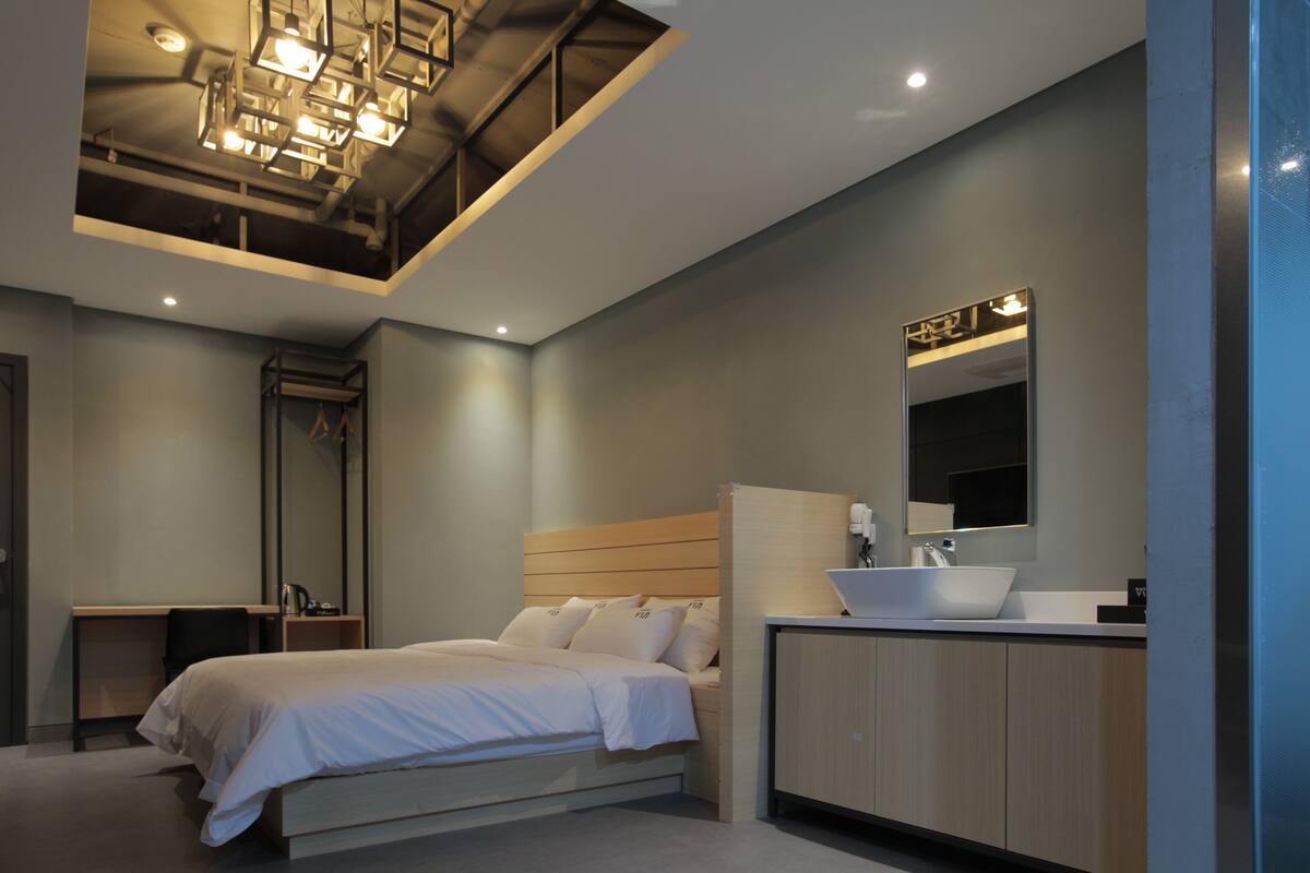 Une chambre à coucher moderne avec un lit, une table de chevet et un grand miroir.