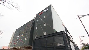 En modern hotellbyggnad med en tydlig skylt som visar hotellets namn, ”Hotel V”.