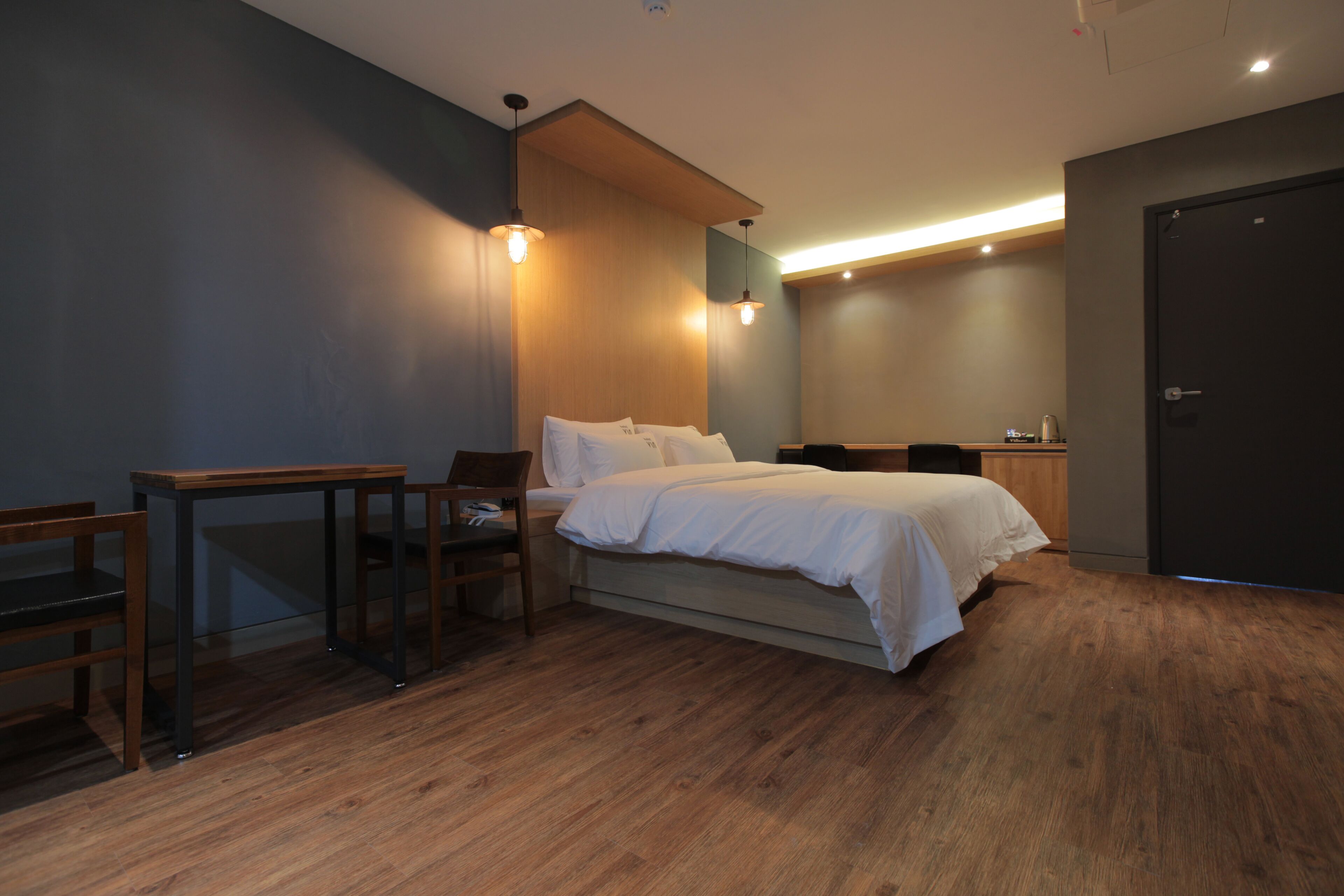 A modern bedroom with a bed, a desk, and a chair.