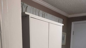 Ein Zimmer mit einem weißen Schrank, einer Tür und einem Fliesenboden.