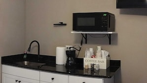 Eine Küchenzeile mit Mikrowelle, Kaffeebereich, Spüle und Schränken.