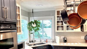 Una cocina moderna con electrodomésticos de acero inoxidable, gabinetes negros y una encimera de mármol.