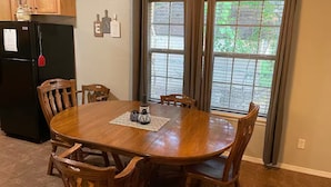A dining area with a wooden table and chairs, a black refrigerator, and a window with curtains. - Cozy Pet-Friendly 3BR Duplex with Fast WiFi only Minutes to Casino (Fort Smith)