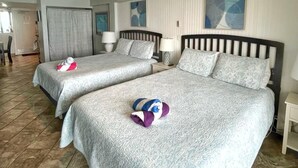 Ein Hotelzimmer mit zwei Betten, einem Deckenventilator und Blick auf den Strand.
