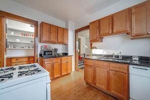 A kitchen with wooden cabinets, a stove, a microwave, and a sink. - The Codfather at Wrigley (Chicago)
