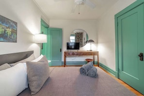 A bedroom with a bed, a desk, a television, a mirror, and a door. - The Codfather at Wrigley (Chicago)