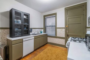 A compact kitchen with a built-in dishwasher, a stove, and a window with blinds. - Keepin’ it Golden at Wrigley (Chicago)