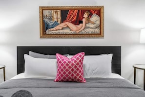 A bedroom with a bed, a framed painting, and a nightstand. - Keepin’ it Golden at Wrigley (Chicago)