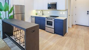 Une cuisine moderne avec des meubles blancs, un réfrigérateur en acier inoxydable, un four à micro-ondes, un four traditionnel et un évier.