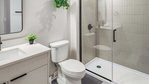 Une salle de bain moderne équipée de toilettes, d’un lavabo et d’une douche à parois en verre.