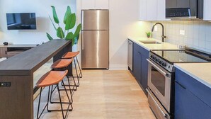 Une cuisine moderne dotée d’un îlot central, d’appareils électroménagers en acier inoxydable et d’un téléviseur à écran plat.
