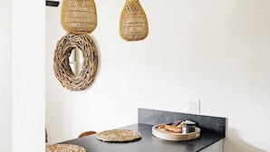 A kitchen with a black countertop, white cabinets, and a black dishwasher. There are woven baskets on the counter and two hanging pendant lights. - Modern and Relaxing Sedona Oasis - Bedouinn (Sedona)