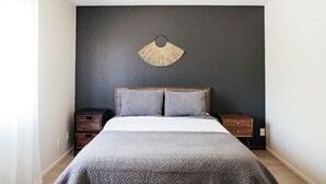 A bedroom with a bed, two nightstands, a wall-mounted fan, and a dark wall. - Modern and Relaxing Sedona Oasis - Bedouinn (Sedona)