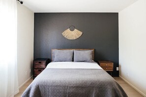 A bedroom with a bed, two nightstands, a wall-mounted fan, and a dark wall. - Modern and Relaxing Sedona Oasis - Bedouinn (Sedona)