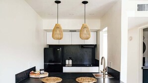 A modern kitchen with black cabinets, a black countertop, two woven pendant lights, and a stainless steel sink. - Modern and Relaxing Sedona Oasis - Bedouinn (Sedona)