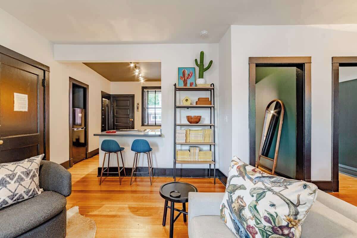 A modern living room with a sofa, a coffee table, and a bookshelf with decorative items.