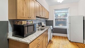 Una cucina compatta con mobili in legno, un forno a microonde, un lavello e una finestra.