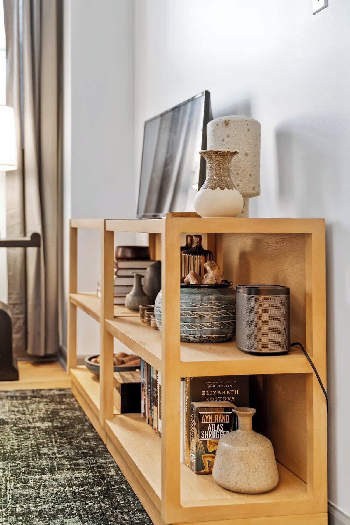 Una estantería de madera con objetos decorativos, libros y una pequeña mesa.