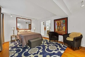 A bedroom with a bed, two armchairs, a bench, a large mirror, and a painting on the wall. - One-of-a-Kind Apartment In Old Town! (Chicago)