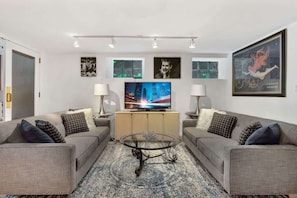 A modern living room with two grey sofas, a glass coffee table, and a flat-screen TV on a wooden cabinet. - One-of-a-Kind Apartment In Old Town! (Chicago)