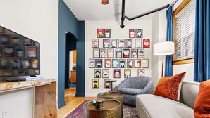 En moderne stue med sofa, sofabord og billedkunst på væggen.