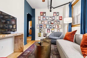 A modern living room with a sofa, a coffee table, and a wall decorated with framed artwork. - A Hand-some Place Near Wrigley (Chicago)
