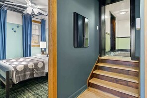 A hotel room with a bed, a desk, a chair, a window with curtains, a ceiling fan, and a staircase. - A Hand-some Place Near Wrigley (Chicago)