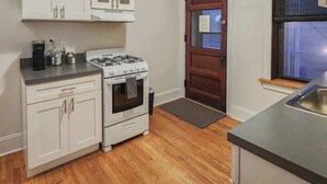 Cozinha compacta com armários brancos, fogão a gás e forno embutido.