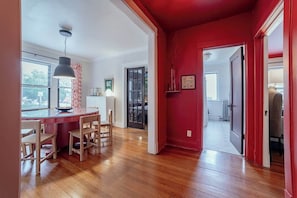 A modern kitchen with a wooden island, a dining area with chairs, and a red accent wall. - The Sassy Sanctuary at Wrigley (Chicago)