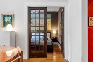 A hallway leading to a bedroom with a large window, a framed picture on the wall, and a sign indicating the direction to the port. - The Sassy Sanctuary at Wrigley (Chicago)