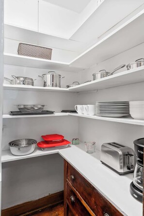 A modern kitchen with white cabinetry, stainless steel appliances, and a variety of cookware and utensils. - The Sassy Sanctuary at Wrigley (Chicago)