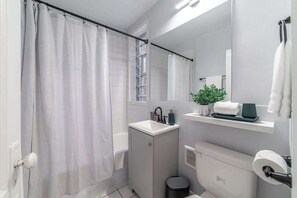 Ein modernes Badezimmer mit Duschvorhang, Waschbecken, Spiegel und Toilette.