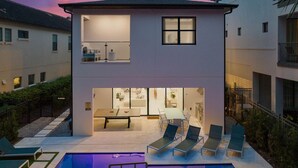 Een modern huis met twee verdiepingen, een zwembad, terras en eethoek.