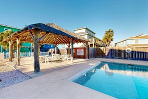 A pool area with a thatched-roof gazebo, outdoor seating, and a clear blue pool. - GV628, Shared Pool, Pet Friendly, Charcoal Grill, Close to Beach (Port Aransas)