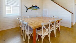 A dining area with a wooden table and white chairs, a ceiling fan, and a fish mural on the wall. - GV634, Shared Pool, Pet Friendly, Charcoal Grill, Close to Beach (Port Aransas)