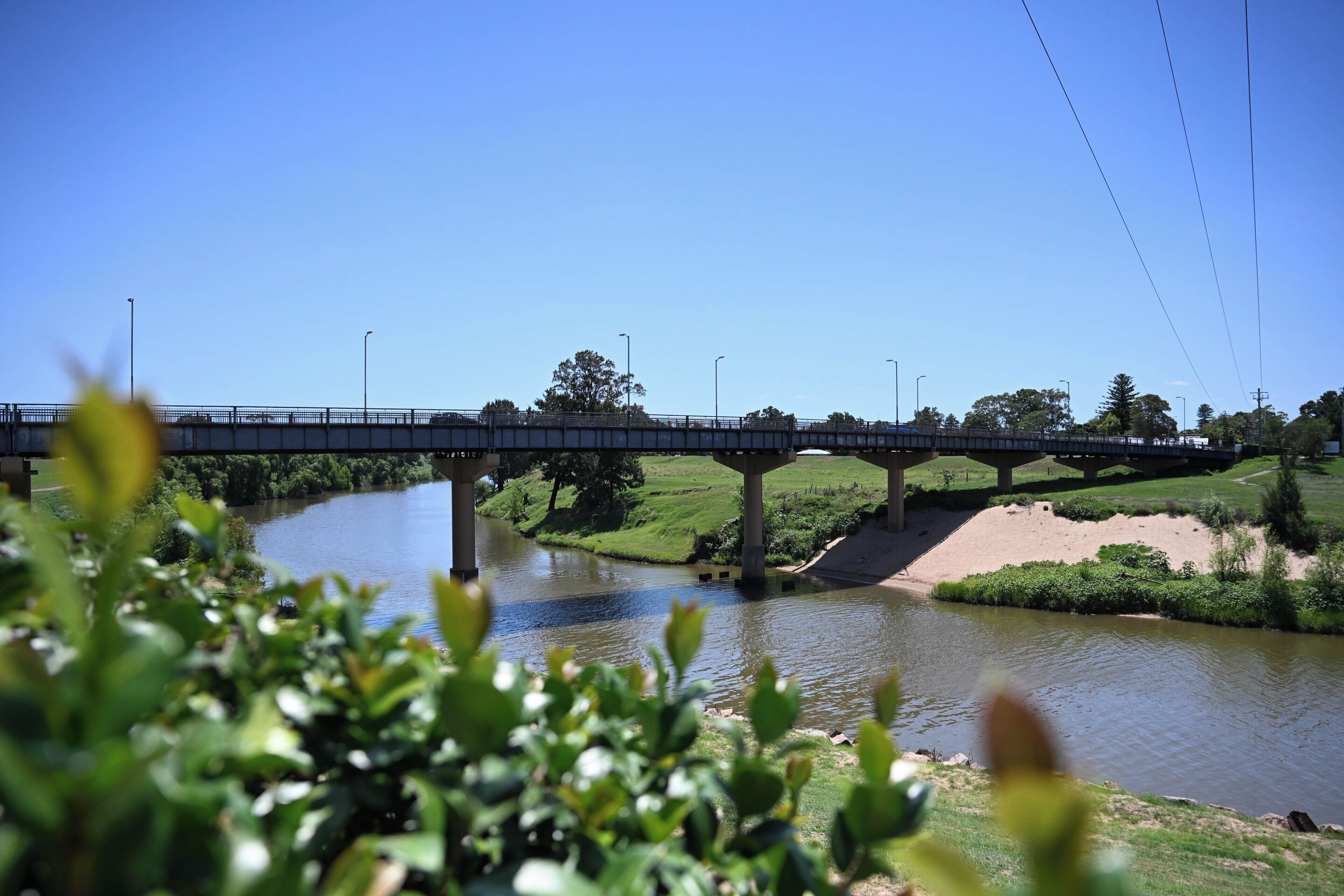 A bridge over a river with greenery on the banks.