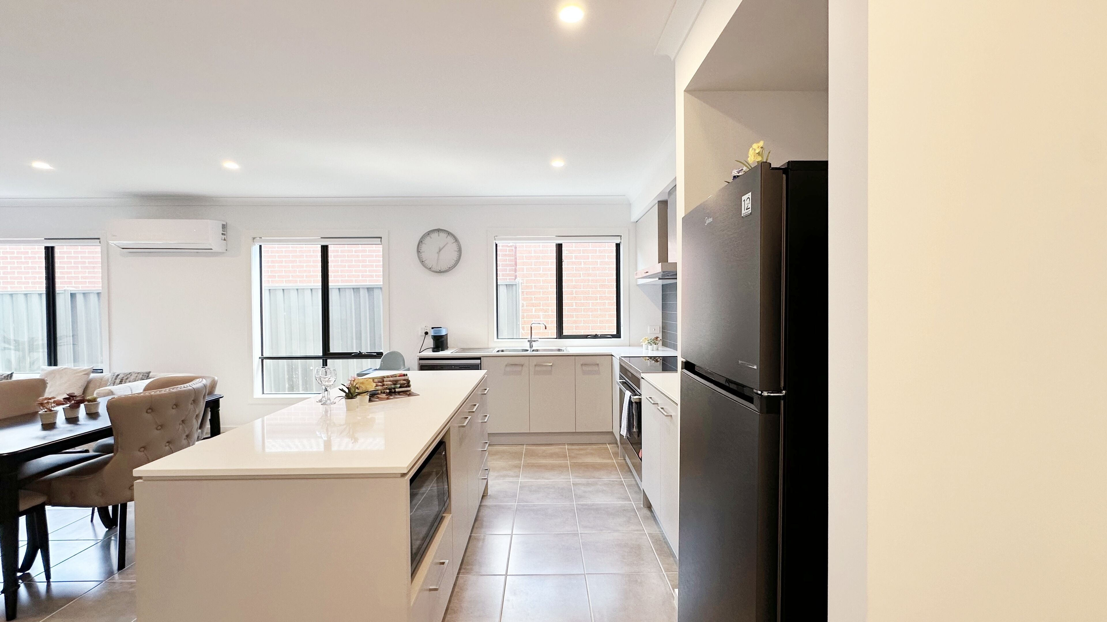 Una cocina moderna con una isla central, un comedor con sofá y sillas, y un refrigerador.