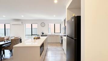 Una cocina moderna con una isla central, un comedor con sofá y sillas, y un refrigerador.