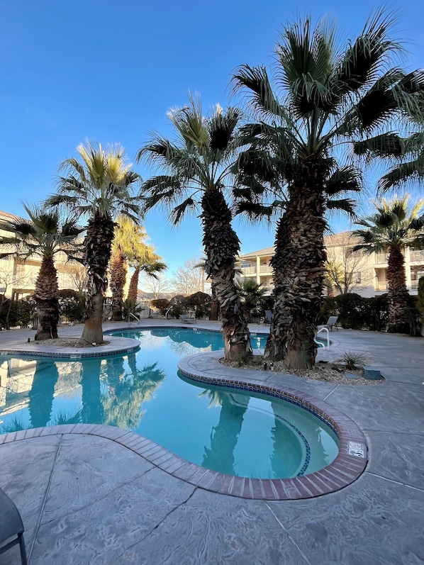A swimming pool surrounded by palm trees, with a clear blue sky above. - The Shandeau: Las Palmas Luxury Condo Overlooking Pools and waterpark. (St. George)